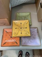 4 square salad plates in orange, yellow, green, and lavender colors with rustic decorative motifs