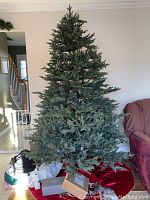 Artificial unlit Christmas tree standing fully assembled showing natural green pine branch spread.