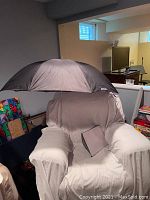 Black Wescott umbrella opened on white armchair showing exterior.