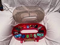 Photo of red oval carrying case with translucent lid containing original Cars The Movie character toy cars