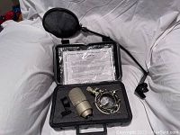 MXL 990 microphone, shock mount, mounting clip, and Pop filter in open black hard case with foam insert.
