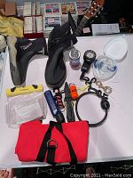 Photo of assorted scuba accessories including boots, regulator, mask, and other small items on table.