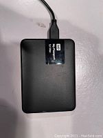 Top view of black external hard drive labeled 'My Passport for Mac' with attached USB cable.
