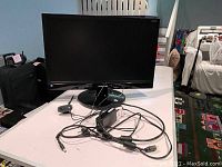 Samsung 24 inch flat panel monitor on a table with power and HDMI cables, and Logitech webcam with cables.