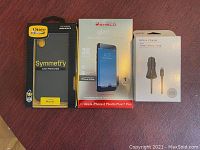 Photo of OtterBox Symmetry case for iPhone XR, InvisibleShield glass screen protector for iPhone 6 Plus/6s Plus/7 Plus unopened, and vehicle charger with lightning connector unopened in their original packaging.