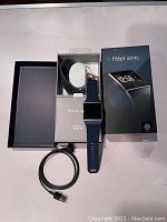 Fitbit Ionic smartwatch laid out with blue strap attached, additional black strap, USB charge cord, instruction manual, and original box with packaging tray.
