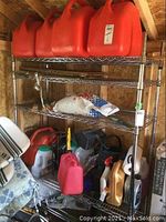 Top shelf showing six red 5 gallon fuel cans, all missing caps with labels visible