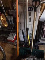 Photo showing multiple long-handled tools including snow shovel, axe, roof rake, bolt cutters, and pole limber arranged together showing overall condition and variety.