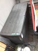 Gray Sun Cast resin deck box with some outdoor wear, photographed from different angles showing its size and condition.