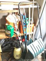 Full view of snow scoop, rakes, sprayer on shelf with various yard and automotive tools