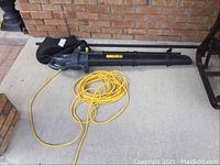 Full view of the Power XT electric leaf blower vacuum with attached yellow extension cord.