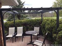 Front-right perspective of pergola over brick-paved patio with chairs