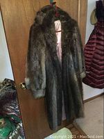 Front view of full-length brown beaver fur coat hanging on door