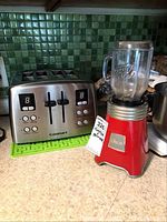Cuisinart stainless steel toaster next to Oster blender on kitchen countertop with green tile backsplash