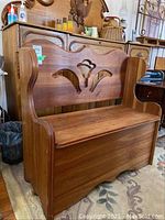 Full side angle view of cherry Deacon's bench showing the curved armrests, decorative back cutout and seat that opens for storage.