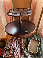 Full view of two-tiered round wooden table with raised edges on top tier, showing wood grain and finish.