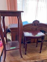 Tall fern stand with square top, curved legs, and lower shelf, showing wear and staining