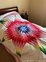 Quilt on wooden bed showing vibrant Lone Star central pattern with red, pink, purple, yellow, and green diamond shapes on white background.