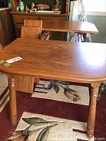 Full view of the solid oak extendable dining table with two additional leafs placed beside it in a room setting.