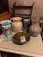 Full view of table with McCoy dishes, jugs, and lamp with hanging crystals