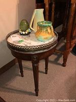 Full view of wooden side table with marble top, two pottery jugs, and decorative egg placed on the table.