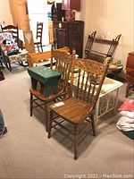 Wide angled photo showing two wooden pressback chairs and the tolle painted green step stool placed on one chair.