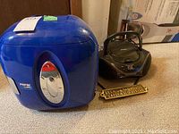 Blue mini Pepsi fridge and black Sylvania Bluetooth CD player radio with small brass sign on carpeted surface