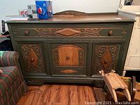 Front view of painted wooden sideboard with carved drawer and cabinet doors