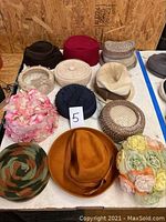 Two tables with various vintage women’s hats arranged in rows showing different colors, styles, and materials.