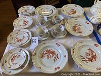 Overview photo showing a full set of Wedgwood & Adams china plates, cups, and saucers with red rooster pattern on a table.
