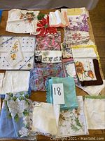 Collection of 18 vintage linen handkerchiefs displayed together with various floral embroidery and lace edges