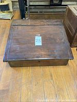 Top view of antique wooden lap desk showing flat rectangular surface with hinges along the fold and aged wood finish.