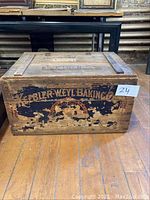 Front view of wooden box showing heavily distressed Keebler-Weyl Baking Co logo and branding with worn black and orange paint.