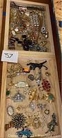 Full tray with multiple pieces of costume jewelry including bracelets, brooches, earrings, necklaces, and pendants in mixed styles and materials.