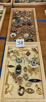 Two wooden trays with assorted costume jewelry including brooches, pins and cufflinks