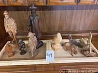 Photo showing all 11 wooden carved figures on a shelf, including folk men and animals (birds, pig)