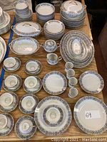 Overview of the Noritake china set including assorted plates, cups, saucers, bowls, and covered serving dishes on wooden table.