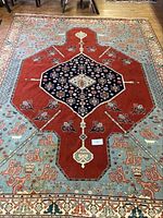 Full view of rectangular rug showing central navy medallion, red field and light blue panels