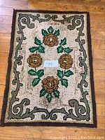 Full view of the vintage hand-hooked floral rug showing overall condition, colors, and border design.