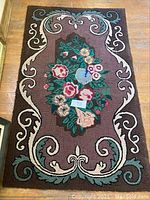 Full view of the vintage hand-hooked rug showing the floral central design and scroll border.