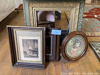 Several picture frames including ornate gold frame, wooden frames with architectural photos, and an oval floral print.