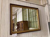 Front view of vintage shadow frame wall mirror showing gold and brown frame and clear reflective glass.