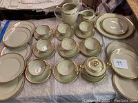Overview of the whole Rosenthal Ivory China set including cups, saucers, plates, sugar bowl, pitcher, and platter, arranged on a table showing the gold trim details.