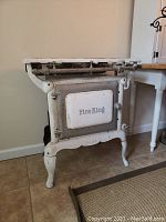 Front angle photo showing the entire Fire King No. 66 stove standing on four legs with a white and grey finish.
