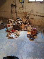 Wide shot of all items on concrete floor showing grouping of nativity scene, Santa figures, gingerbread man, signs, jack o' lantern lantern, and bowls
