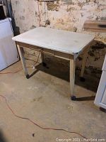 Front angle of vintage metal kitchen table showing tabletop surface, legs, and floor placement.