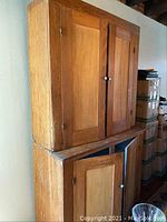 Front view of the large vintage wooden cupboard with hutch showing double wooden doors and round metal knobs