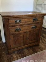 Front view of antique wood cabinet showing two drawers with metal handles and double doors below.