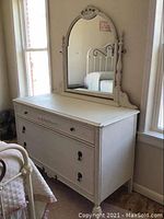 Full view of the dresser with mirror showing overall shape, color, and placement next to window and bed.