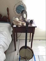 Vintage banjo and vanity mirror on bedside table with lace pieces and hairpin